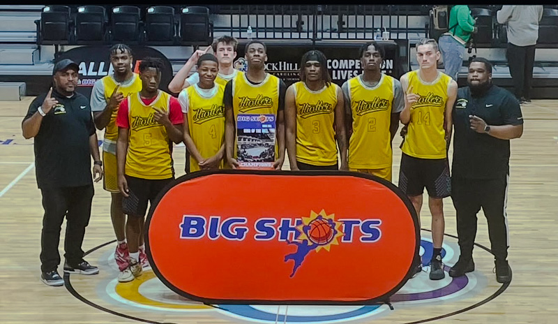 Hustlers Traveling Boys Basketball Team in yellow uniforms standing in front of a "Big Shots" sign